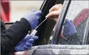  ?? MATT ROURKE — THE ASSOCIATED PRESS FILE ?? A driver places a swab into a vial at a free drive-thru COVID-19testing site in the parking lot of Mercy Fitzgerald Hospital in Darby, Pa., on Jan. 20.