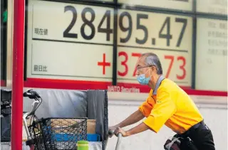  ?? AP PHOTO ?? A man carries delivery boxes past monitors showing Japan’s Nikkei 225 index at a securities firm in the capital Tokyo on Thursday, Nov. 24, 2022.