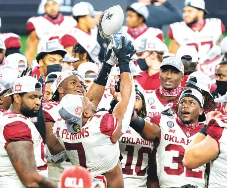  ?? AP PHOTO/JEFFREY MCWHORTER ?? Oklahoma’s Ronnie Perkins (7) hoists the Big 12 Conference championsh­ip trophy as the Sooners celebrate their 27-21 win over Iowa State on Saturday in Arlington, Texas.