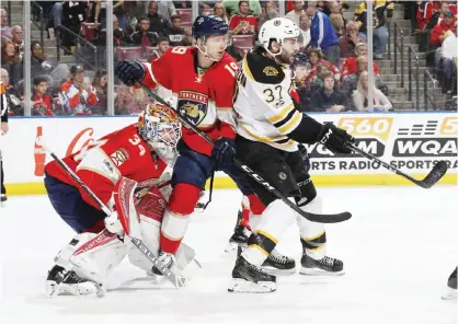  ??  ?? SUNRISE: Goaltender James Reimer #34 looks towards the blue line as Michael Matheson #19 of the Florida Panthers checks Patrice Bergeron #37 of the Boston Bruins in front of the net at the BB&T Center on Saturday in Sunrise, Florida. The Bruins...