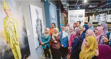  ?? PIC BY AIZUDDIN SAAD ?? Selangor Land and Mines Department employees admiring a photograph of Yang di-Pertuan Agong AlSultan Abdullah Ri’ayatuddin Al-Mustafa Billah Shah Sultan Ahmad Shah Al-Musta’in Billah at the ‘The Monarch’ exhibition at Galeri Prima in Bangsar yesterday.