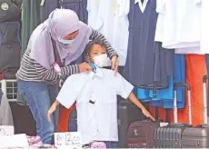  ?? – Photo by Muhammad Rais Sanusi ?? A mother checking out the size of a school uniform for her son in Kuching recently.