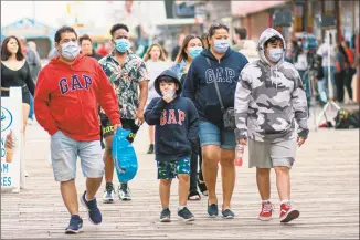  ?? Kena Betancur / AFP via Getty Images ?? People wear face masks as they walk on the boardwalk in Seaside Heights, N.J., on Sunday.