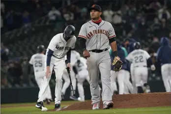  ?? TED S. WARREN — THE ASSOCIATED PRESS ?? Giants second baseman Donovan Solano walks off the field as the Mariners celebrate after Jake Fraley was walked with the bases loaded during the 10th inning on Thursday in Seattle. The Mariners won 8-7.