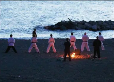  ?? JONATHAN TRESSLER — THE NEWS-HERALD ?? Six black-belt candidates from the Madison Combined Martial Arts Associatio­n, a 30-year-old Madison Village business, maintain their Kiba Dachi stance on the beach at Madison Township Park in the early morning hours of June 23.