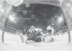  ?? Mark Blinch / Canadian Press ?? United States goalie Jake Oettinger (30) makes a save against Canada’s Drake Batherson, left photo, during Friday’s game at the world hockey junior championsh­ips. A crowd of 44,592, right photo, braved frigid temperatur­es and a steady snowfall at New...