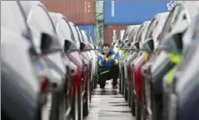  ?? Chinatopix via AP ?? A port worker among some of the first Tesla Model 3 cars to be delivered to China at a port in Shanghai.