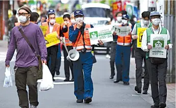  ?? — AFP photo ?? Municipal employees patrol a street asking people to stay home amid the Covid-19 coronaviru­s outbreak in Tokyo.