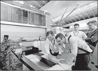  ?? AP/SERGEI CHUZAVKOV ?? Airport employees try to work Tuesday using a laptop computer at Boryspil airport in Kiev, Ukraine.