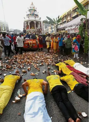  ??  ?? Holy act: Devotees lying on the road after breaking coconuts to fulfil their vows during the procession of the Lord Muruga chariot in Kuala Lumpur for Thaipusam.