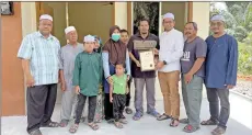  ?? ?? Mohammed Fariz (fourth right) receiving the keys and home title from Parit Ya’ani assemblyma­n Datuk Najib Samuri at Kampung Parit Banyumas, Parit Ya’ani yesterday.