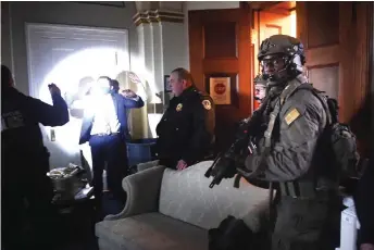  ??  ?? Congress staffers hold up their hands while Capitol Police Swat teams check everyone in the room as they secure the floor of Trump suporters.