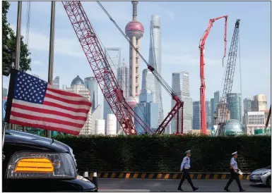  ?? (AP) ?? Chinese traffic police officers walk by a U.S. flag on an embassy car on July 30 outside a hotel in Shanghai where officials from China and the United States met for talks aimed at ending a tariff war.