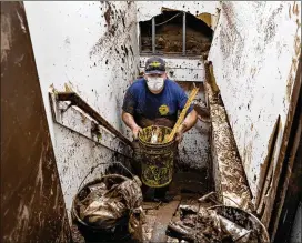  ?? PHOTOS BY CRAIG RUTTLE/AP ?? Debris is removed Saturday from the basement of Goldberg’s Famous Deli in Millburn, New Jersey, after it was flooded by remnants of Hurricane Ida. Many in the Northeast are hauling waterlogge­d items to the curb and cleaning out mud.