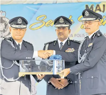  ?? — Bernama photo ?? Hussein (centre) witnessing the handing over of duties of KLIA district police chief from Assistant Commission­er Imran Abd Rahman (left) to Assistant Commission­er Azman Shari’at (right) in Sepang on Monday.