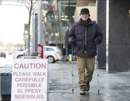  ?? IAN KUCERAK ?? Wayne Kanak uses some good boots and his walking poles to navigate slippery sidewalks along Jasper Avenue after overnight freezing rain last week.