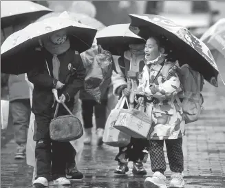  ?? SHAO DAN / FOR CHINA DAILY ?? Students walk into the Fuzimiao Elementary School campus on a rainy day in Nanjing, Jiangsu province, on Wednesday, as the new semester begins.