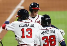  ?? Kevin C. Cox, Getty Images ?? Freddie Freeman, center, and Ronald Acuna Jr., left, embrace during a game in April 2021.