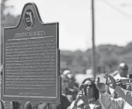  ?? THOMAS BENDER/HERALD-TRIBUNE ?? People take photos Feb. 24 of the Lynching in America marker behind the Unitarian Universali­st Church, on Fruitville Road, in Sarasota. The marker bears the names of six Black men killed in lynchings in the area, now Manatee and Sarasota County.