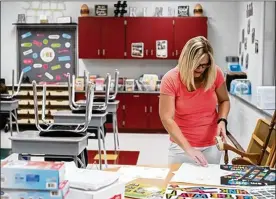  ??  ?? Jody Dixon, a fifth-grade reading teacher, hangs posters in her classroom in preparatio­n for the upcoming year earlier this month at Jasper Elementary School in Jasper. Dixon was a teacher at Zahn’s Corner Middle School, but students and teachers relocated after the middle school closed.