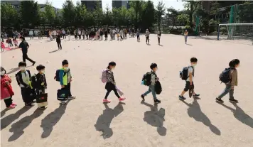  ?? | AP ?? PUPILS wearing face masks as a precaution against the new coronaviru­s, walk to their classrooms while maintainin­g social distancing after they attend the entrance ceremony at Chungwoon elementary school in Seoul, South Korea.