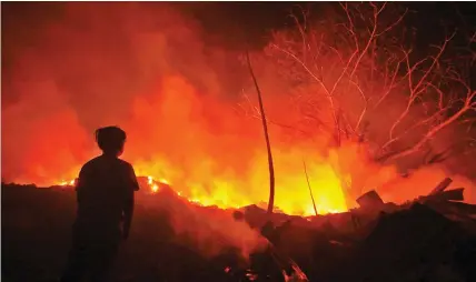  ??  ?? A boy stares at the fire that hit the landfill in Barangay Inayawan, Cebu City Sunday night. Firefighte­rs were able to contain and control the fire in less than two hours. No one was hurt in the incident. ALDO NELBERT BANAYNAL