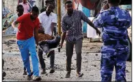  ?? AP/FARAH ABDI WARSAMEH ?? Somalis carry away a person wounded in one of the bomb blasts Friday at the Sahafi Hotel in Mogadishu.