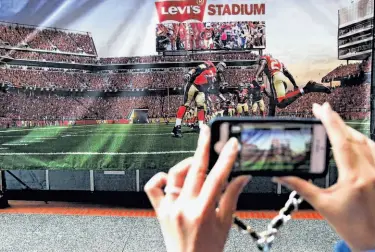  ?? Lance Iversen / The Chronicle ?? A visitor takes a photo of an artist’s rendering of what Levi’s Stadium in Santa Clara will look like.