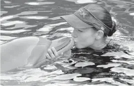  ?? CHRIS O’MEARA / AP ?? Clearwater Marine Aquarium senior marine mammal trainer Abby Stone kisses Winter the dolphin during an Aug. 31, 2011, show in Clearwater.