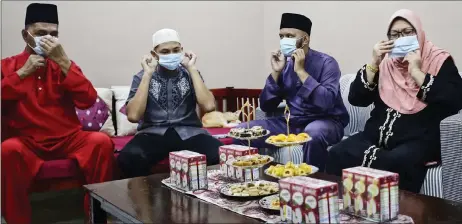  ??  ?? Muhd nur azmi (left) and his family don facemasks while getting ready to celebrate raya aidilfitri yesterday evening. — bernama photo