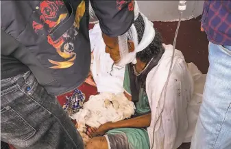  ?? Associated Press 2020 ?? An elderly woman, who fled to the city of Axum in the Tigray region of Ethiopia to seek safety, sits with her head bandaged after being wounded during an attack on the city in November.