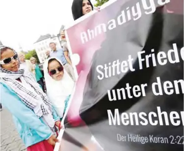  ?? — AFP ?? COLOGNE: Two girls stand next to a banner citing the Quran and reading ‘Make peace among the people’ as they take part in a so-called ‘Ramadan Peace March’ of Muslims and friends against terrorism and violence in Cologne, western Germany yesterday.