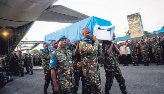  ?? AFP ?? Soldados de Tanzania cargan el ataúd de un miembro de las Fuerzas de Paz de la ONU. Catorce soldados tanzanos de los cascos azules murieron en Kivu del Norte, República Democrátic­a del Congo, el jueves anterior, durante un ataque de presuntos rebeldes...