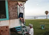  ?? Jon Shapley / Staff photograph­er ?? Larry Willis, left, and Jim Ethridge board up Willis’ home Tuesday in Smith Point.