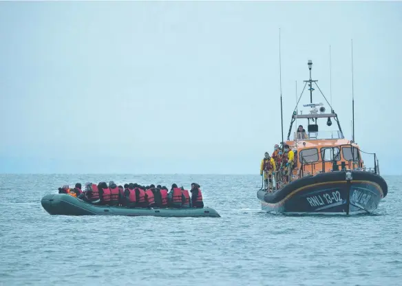  ?? ?? Migrants are helped by lifeboat before being taken to a beach in Dungeness, on the southeast coast of England. Picture: AFP