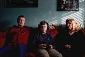  ?? STEPHEN SPERANZA / NEW YORK TIMES ?? John and Cathleen Reichert watch as their son, James, plays video games at their home Jan. 15 in Boulder, Colo.. Children’s screen time had doubled by May as compared with the same period in the year prior, according to Qustodio.