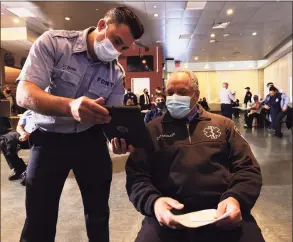  ?? Michael M. Santiago / Getty Images ?? Members of the FDNY EMS speak in the waiting area while receiving the coronaviru­s vaccine last week in New York City.