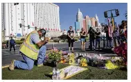  ?? GINA FERAZZI / LOS ANGELES TIMES ?? Contractor Robert Walker says a prayer after placing flowers and an American flag at the scene of a memorial on Las Vegas Boulevard for the victims of the mass shooting Sunday night.