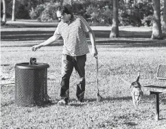  ?? Associated Press ?? ■ Emmanuel Cabrera properly disposes of his dog’s poop in a trash can at Kennedy Dog Park in Coconut Grove, Fla.