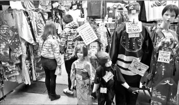  ??  ?? Chinese tourists shop at a kimono store in the Asakusa district of Tokyo.