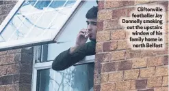  ??  ?? Cliftonvil­le footballer Jay Donnelly smoking out the upstairs window of his family home innorth Belfast