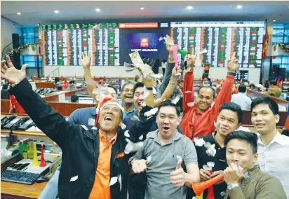  ?? (Ezra Acayan/Reuters) ?? TRADERS THROW confetti as they celebrate the end of trading for 2016 at the Philippine Stock Exchange in Manila yesterday.