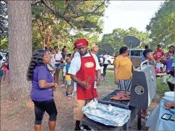  ?? Robyn James ?? Above: Amber Jackson talks to her husband, Roderick, as he mans the grill at Zion Hill Baptist Church in Rockmart on Sunday. Left: Shay Alexander and Mekaela King prepare cake donated by Mac’s Bakery. Below: Desmond, one of Cummings’ three children, smiles and wears a shirt with a picture of his dad on it at a gathering Sunday to not only remember him — but to also put an end to violence.