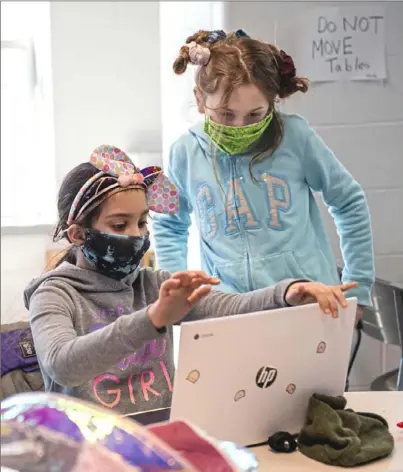  ?? Emily Matthews/Post-Gazette ?? Fourth graders Carina Adams, 9, left, and Evie McCrimmon, 9, pack up their laptops Friday at Estelle S. Campbell Boys & Girls Club in Lawrencevi­lle. The location is one of 60 “learning hubs,” where Pittsburgh Public Schools students can access internet, learn and play during ongoing school closures.