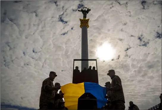  ?? VADIM GHIRDA — THE ASSOCIATED PRESS ?? Ukrainian servicemen place the national flag on the coffin of fallen comrade Vadym Popelniuk, born in 1991, during a religious service Friday in Independen­ce Square in Kyiv.