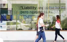  ?? — Reuters ?? People walk past an Uber advertisem­ent outside the Uber main office in Mandaluyon­g city, metro Manila, Philippine­s.