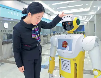  ?? ZOU HONG / CHINA DAILY ?? A staff member interacts with Xiaofa, a robot that provides simple legal advice and guidance for litigants, at Beijing No 1 Intermedia­te People’s Court on Thursday.