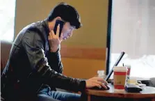  ?? — Reuters ?? A man talks on the phone as he surfs the internet on his laptop at a local coffee shop in downtown Shanghai.