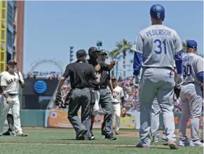  ?? (Photo by Ben Margot, AP) ?? Home plate umpire Mike Muchlinski, center, separates Los Angeles Dodgers, right, from San Francisco Giants in the middle of the third inning of Wednesday's game.