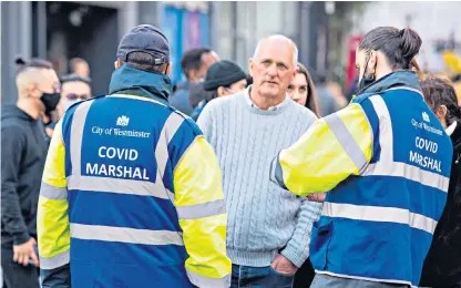  ?? ?? Move on: Covid marshals speak to members of the public in Soho, central London, last April